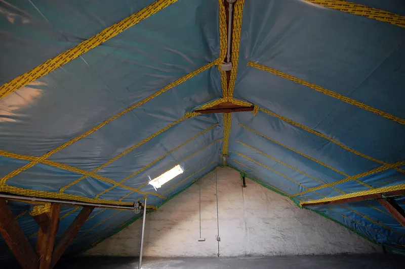 Isolatiemateriaal wordt aangebracht tussen de dakbalken